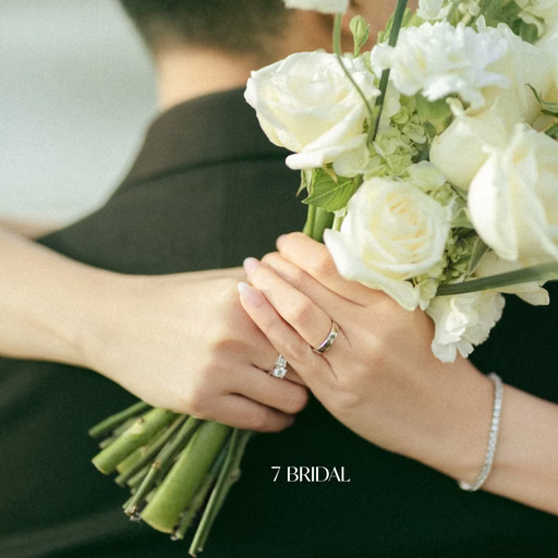 Close-up of the bride's ringed hand and white bouquet over the groom's shoulder at Cây Thông Cô Đơn, Đà Lạt