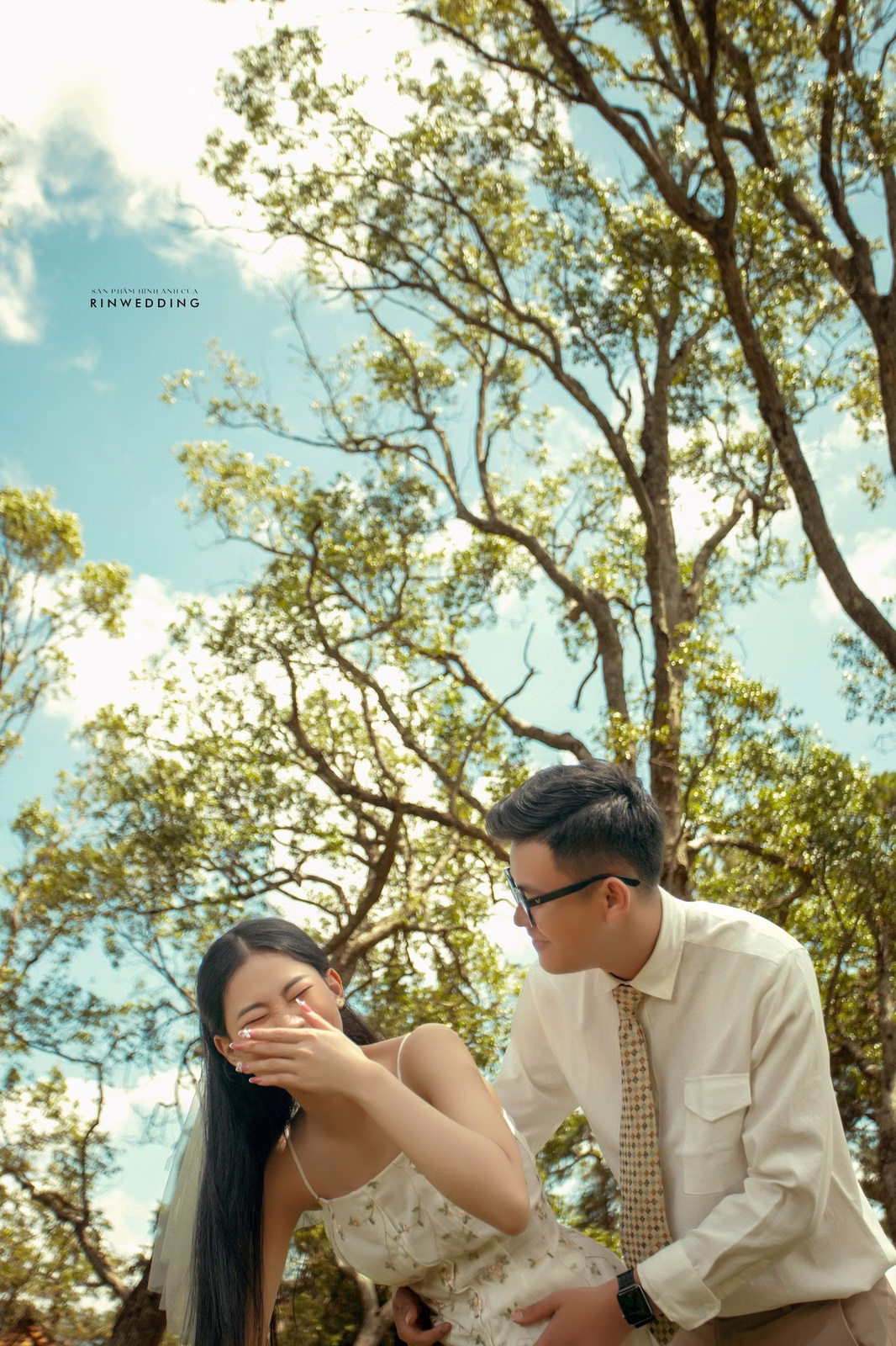 The groom covering the bride’s eyes beneath trees at Dinh Tỉnh Trưởng.