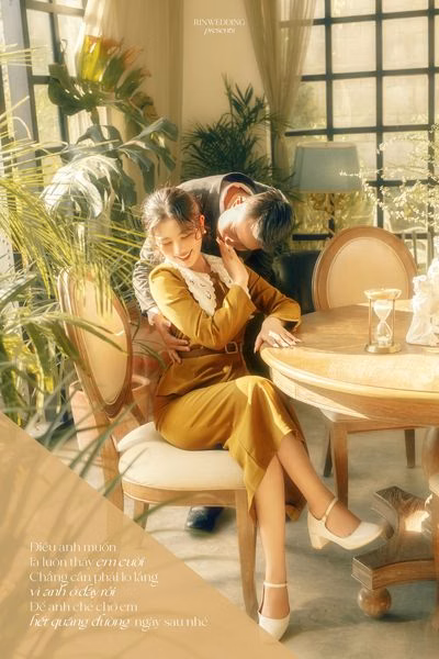 The man leans in to kiss the woman in a yellow dress beside a tea table at a Đà Lạt café.