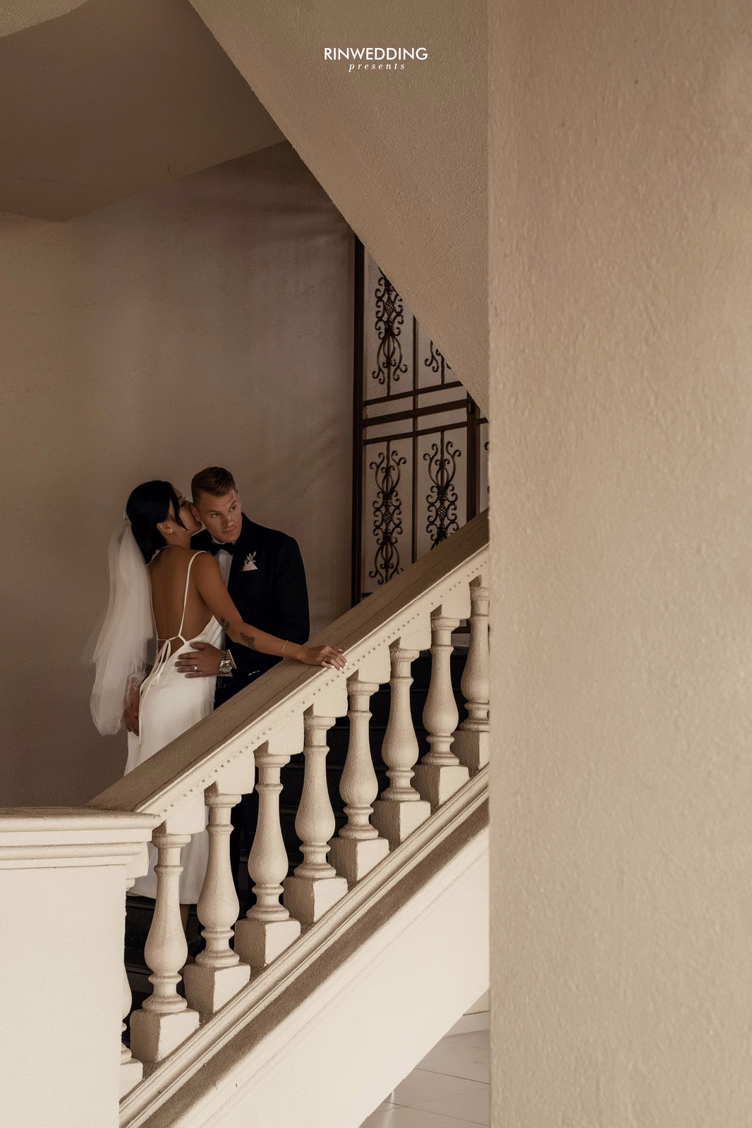 The bride and groom lean close beside the stair railing at Don Bosco Đà Lạt.