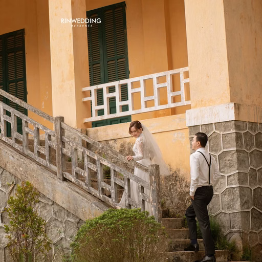 The couple stands on stone steps at Dinh Tỉnh Trưởng.