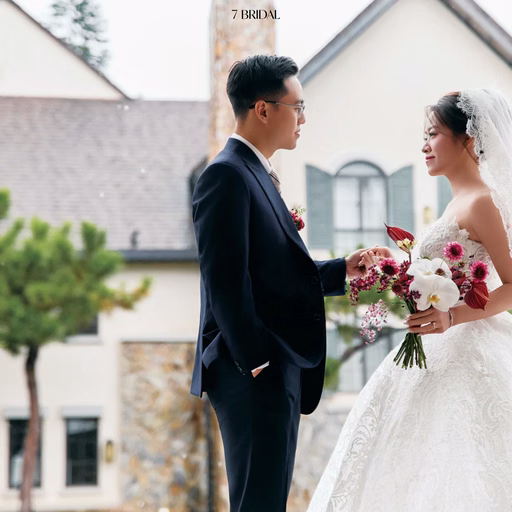 A bride and groom face each other before a white villa.