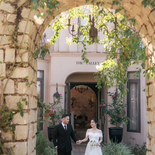 The couple walk through a greenery-covered arch at The Nest, Đà Lạt