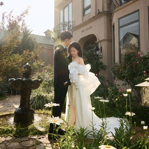 A couple beside a small pond in front of a building among daisies at The Nest, Đà Lạt