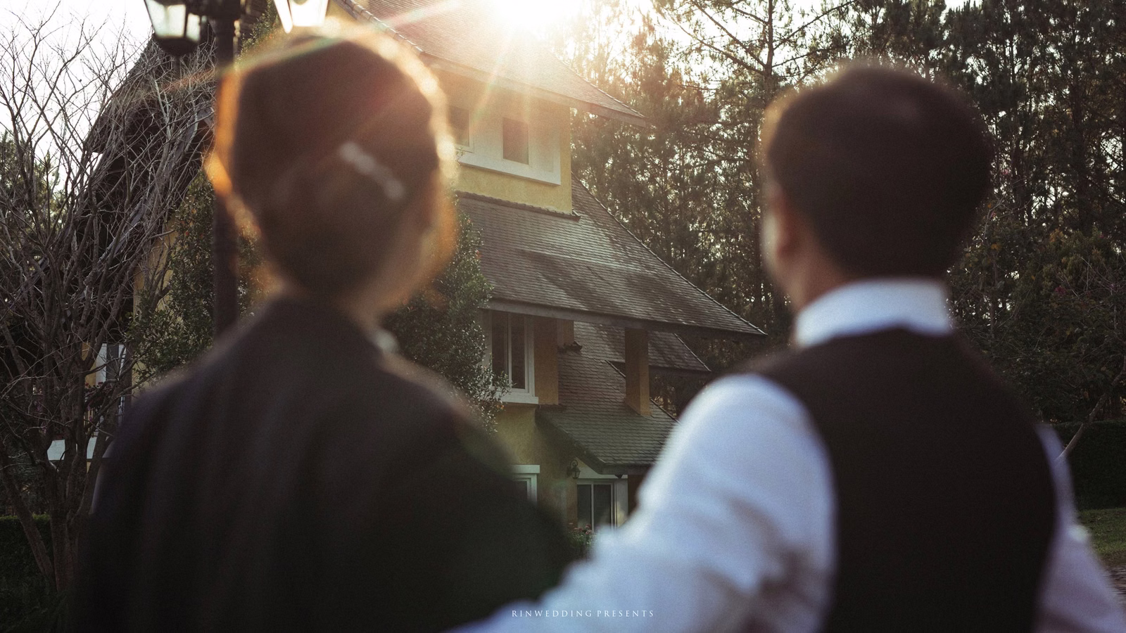 Rear view of the couple looking toward a sunlit villa.