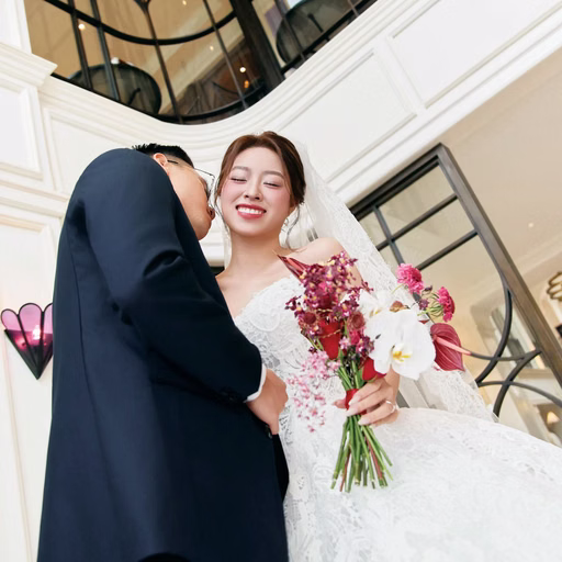 The bride laughs as the groom leans close on the stairs.