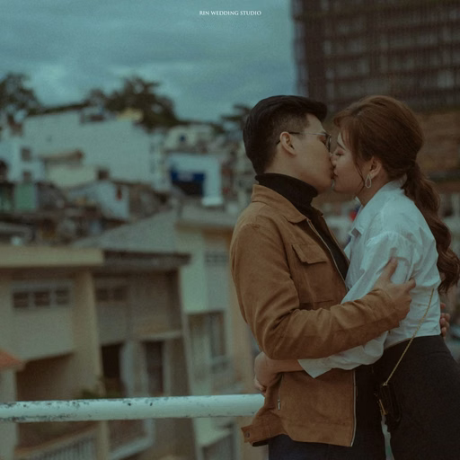 The couple embrace on a balcony overlooking Đà Lạt rooftops.