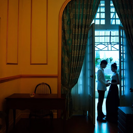 The couple faces each other beside a window in a warmly lit room.