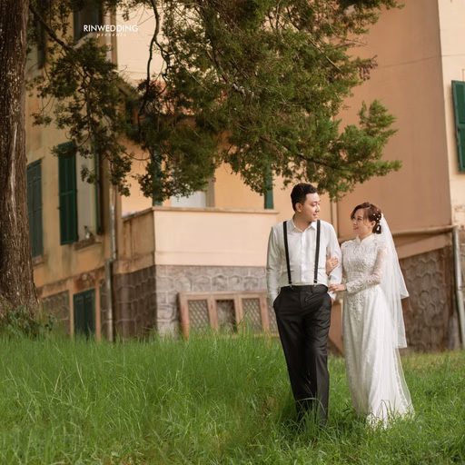 The bride and groom walking on the lawn before Dinh Tỉnh Trưởng.