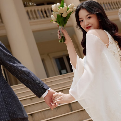 The bride holding flowers and looking back while holding the groom's hand at Nhà thờ Don Bosco