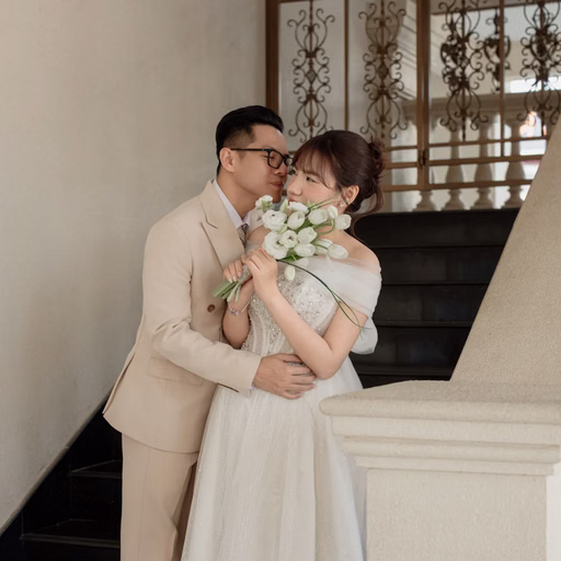 The bride and groom embrace beside the staircase at Nhà thờ Don Bosco