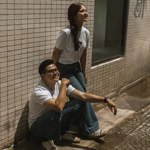 The couple in white posing beside a brick wall outside a Da Lat café.