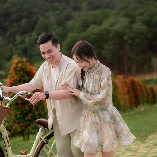 Cặp đôi cười bên chiếc xe đạp có giỏ trên lối đi vườn hoa tại Hoa Trong Rừng, Đà Lạt