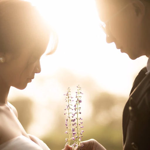 The bride and groom raising glasses in sunlight filtering through the garden.