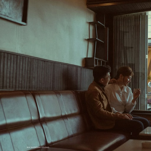 The couple sitting close on a long leather sofa in a nostalgic café.
