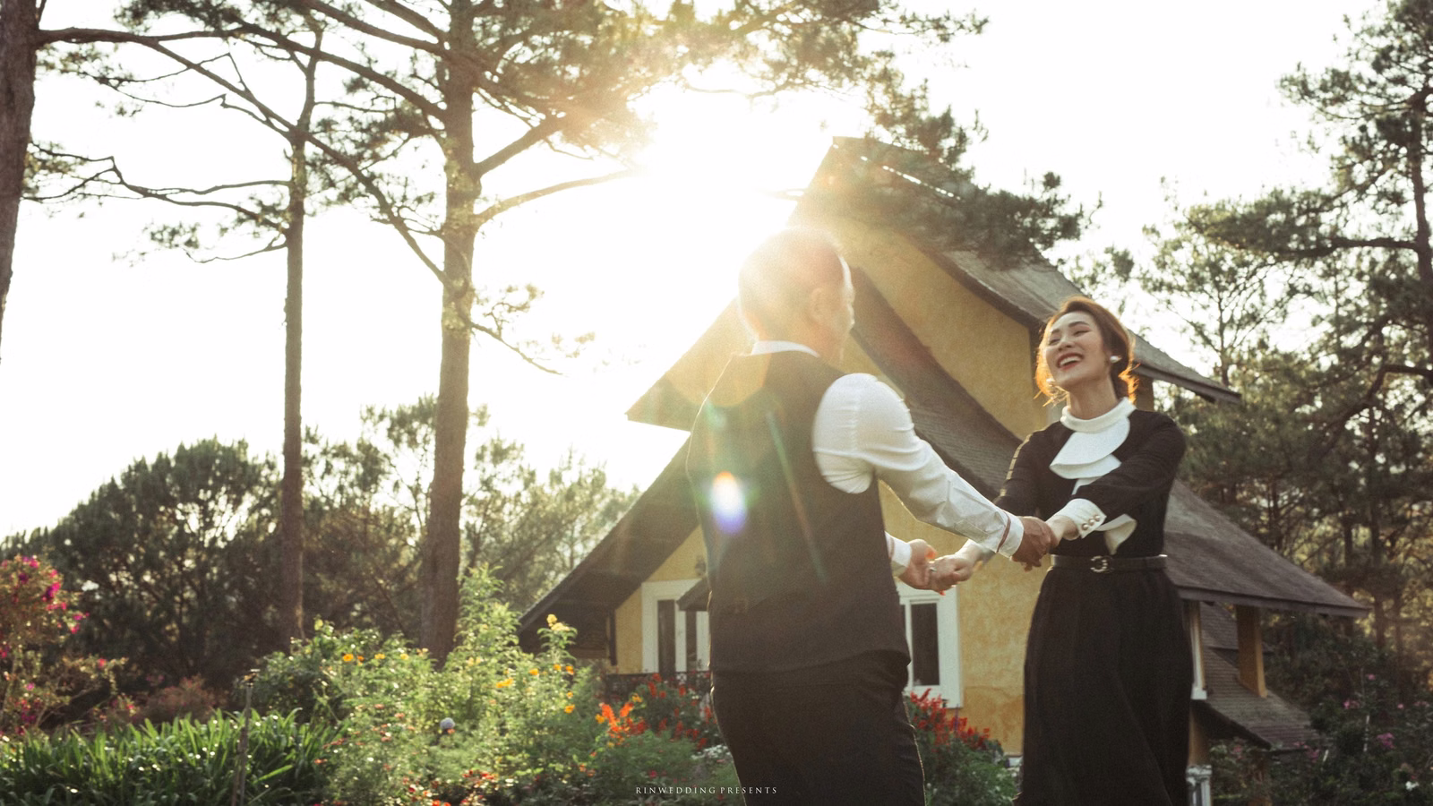 A bride and groom hold hands and play in a sunlit garden.