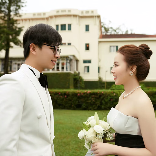 A bride and groom look at each other before a historic building.
