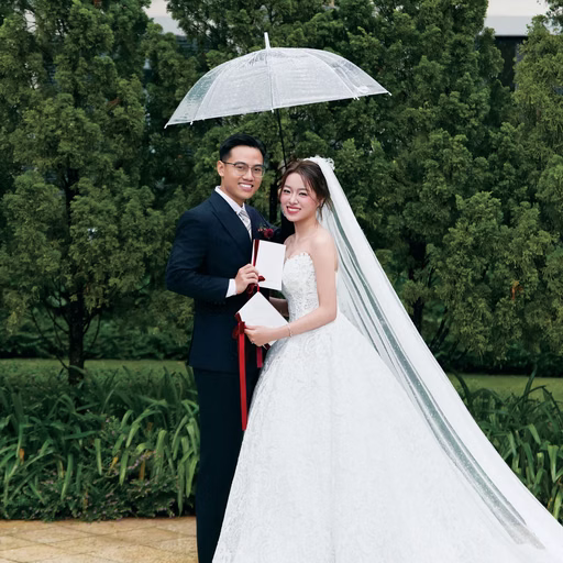 The bride and groom holding an umbrella together in a lush resort garden.