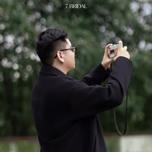 A man holds up his phone to take photographs in a Đà Lạt café garden.