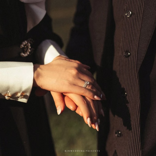 Close-up of the bride's hand resting on the suited groom's hand.