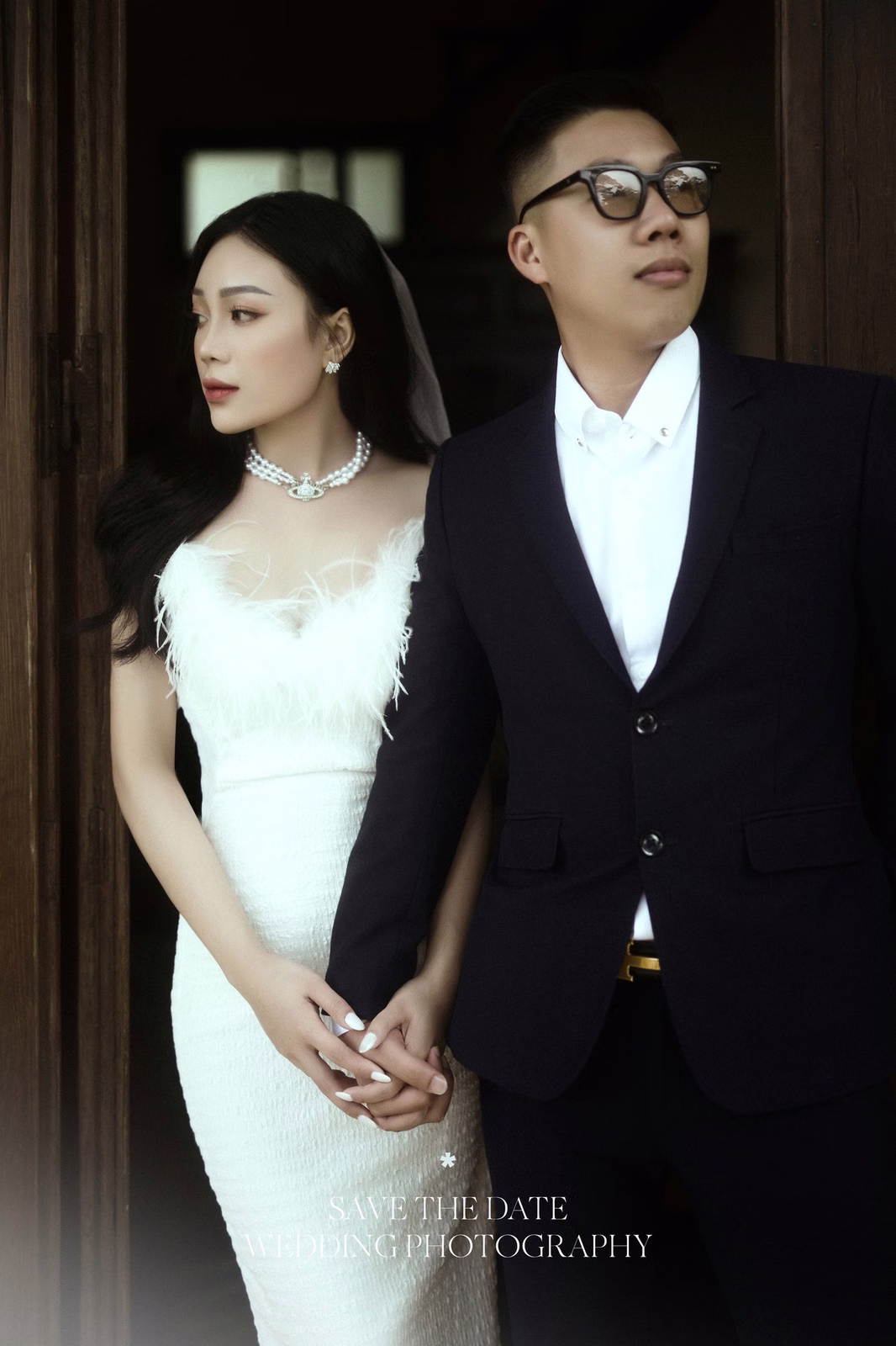 The couple holds hands before a villa's wooden door.