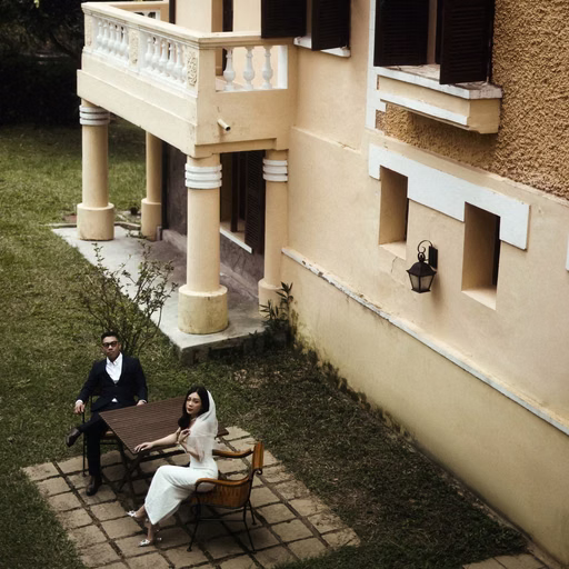 An overhead view of the bride and groom before a yellow villa.