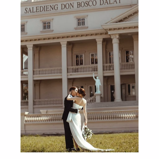 The bride and groom embrace before the colonnade at Nhà thờ Don Bosco