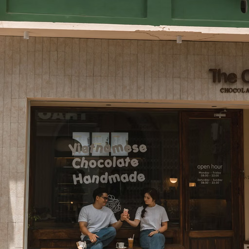 The couple sits in sunshine outside a chocolate shop in Đà Lạt.