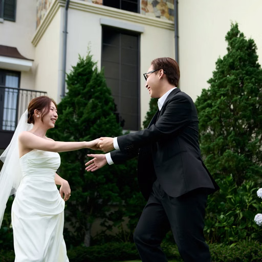 The couple holds hands and twirls on a resort lawn.