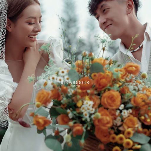 A close-up of the bride and groom with an orange and white bouquet.