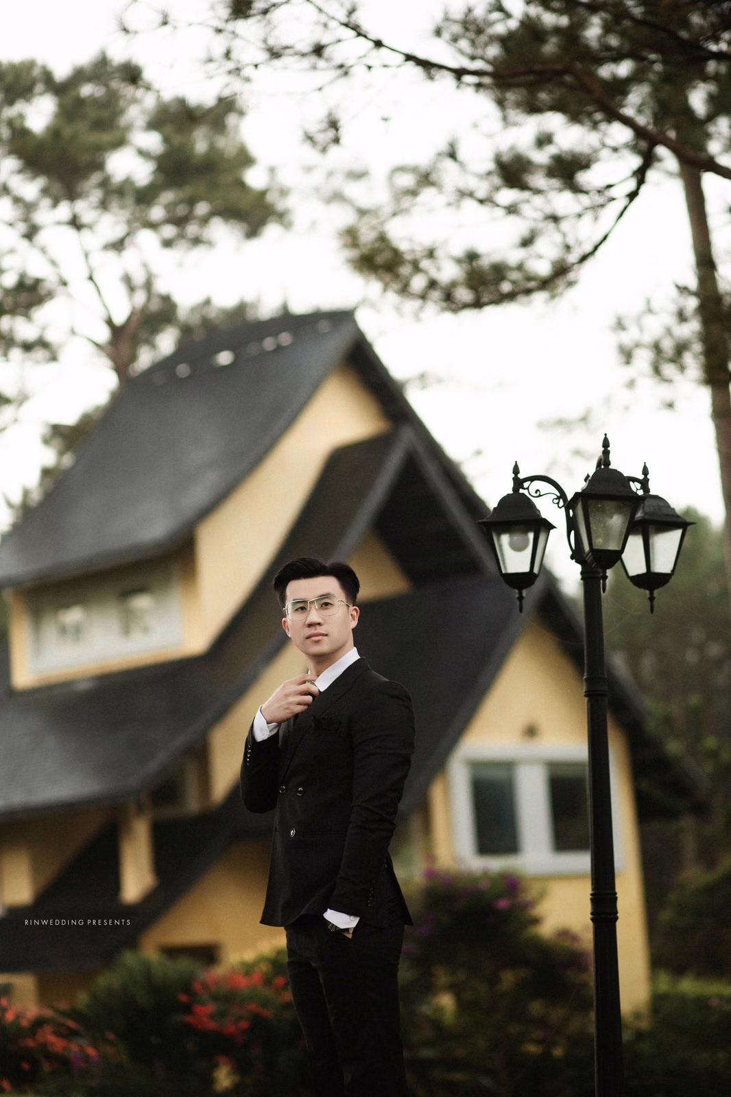 The groom adjusts his bow tie before a steep-roofed villa in the resort.