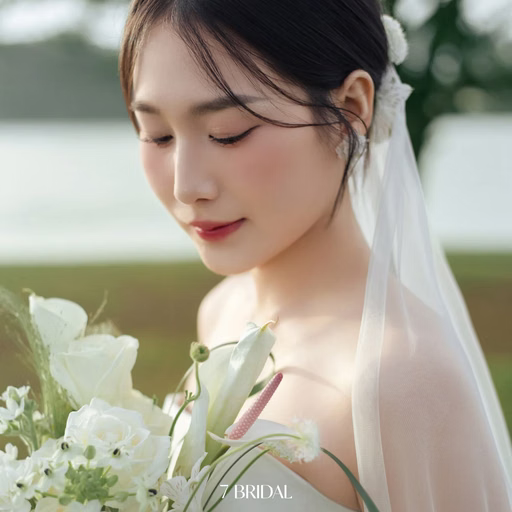 Portrait of the bride looking at her white bouquet, with decorative lettering, at Cây Thông Cô Đơn, Da Lat