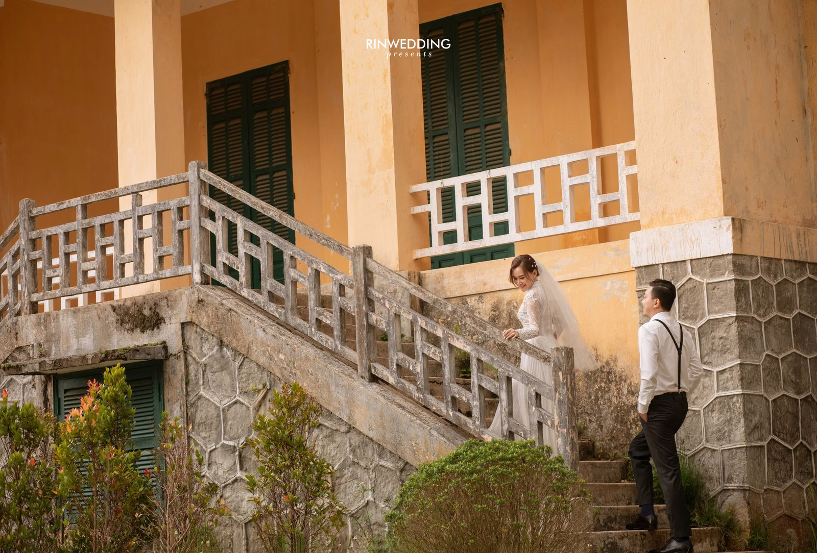 The couple stands on stone steps at Dinh Tỉnh Trưởng.