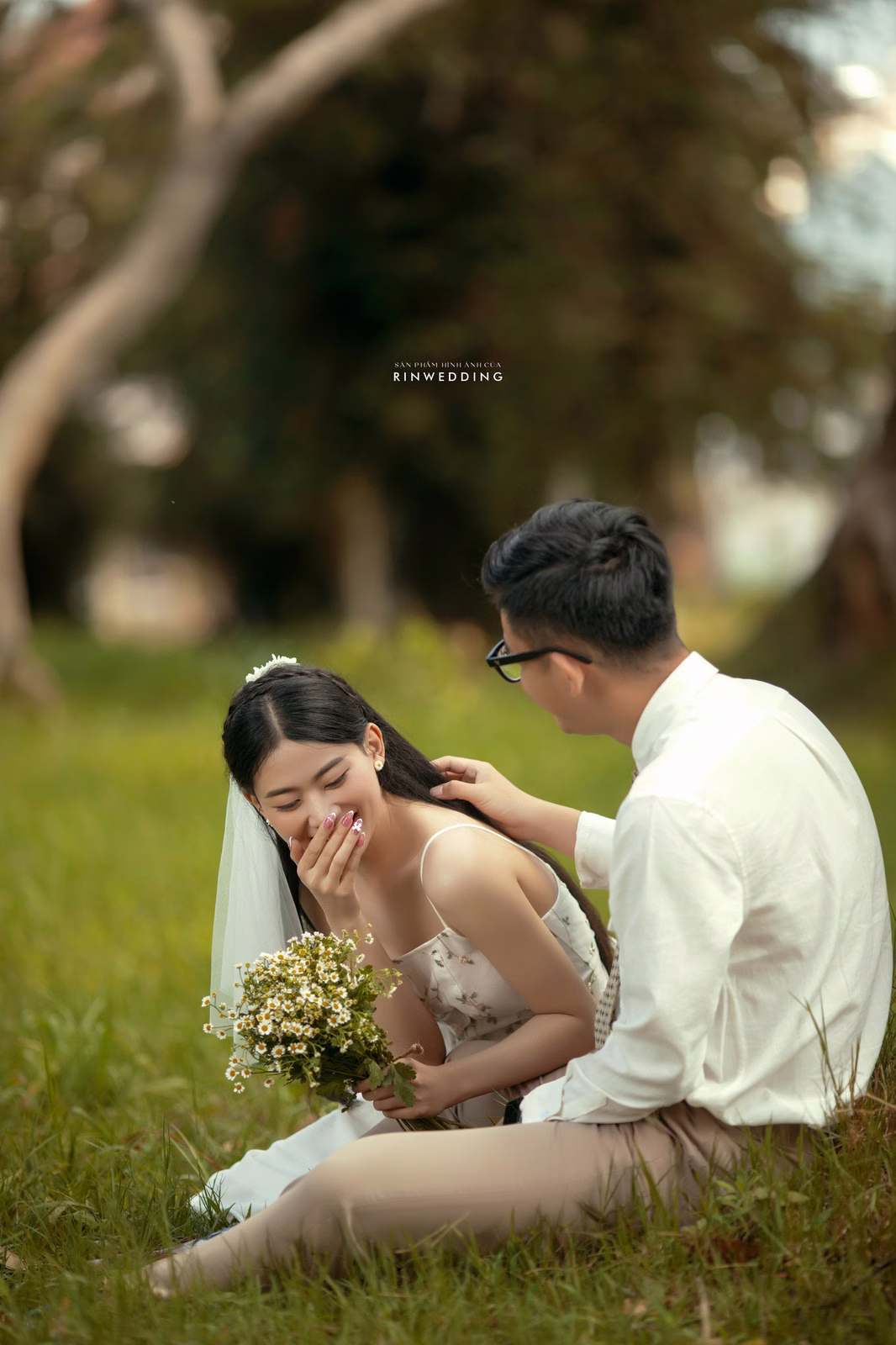 A couple sitting and smiling beside a bouquet in the garden of Dinh Tỉnh Trưởng.