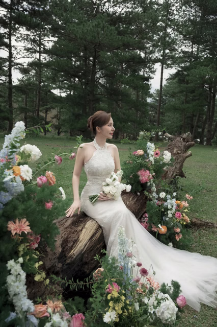 Cô dâu ngồi trên thân cây trang trí hoa giữa bãi cỏ tại Đồi Trọc Đà Lạt