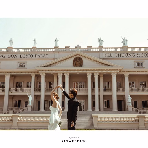 The groom raising the bride’s hand before the façade of Nhà thờ Don Bosco