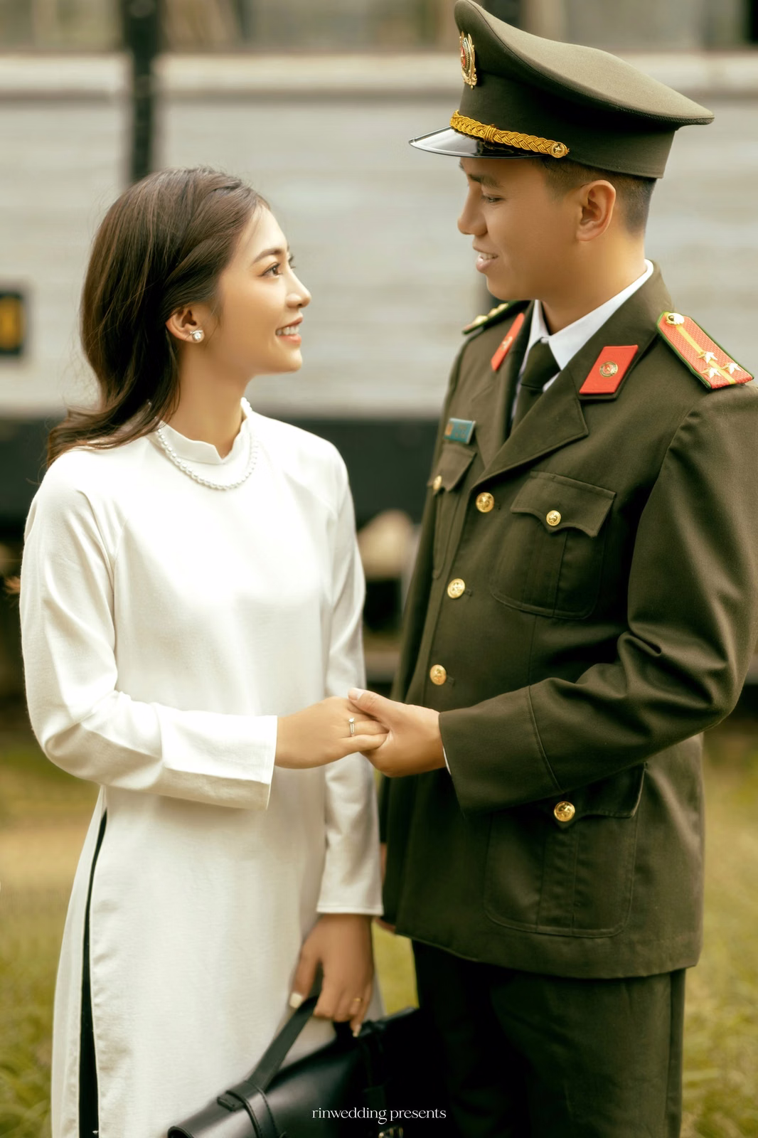 The couple holding hands and looking at each other beside a carriage at Ga Đà Lạt.