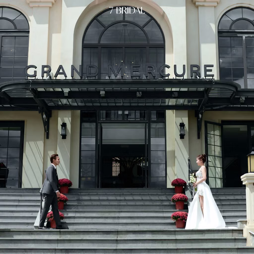 The couple stands on steps outside Grand Mercure hotel.
