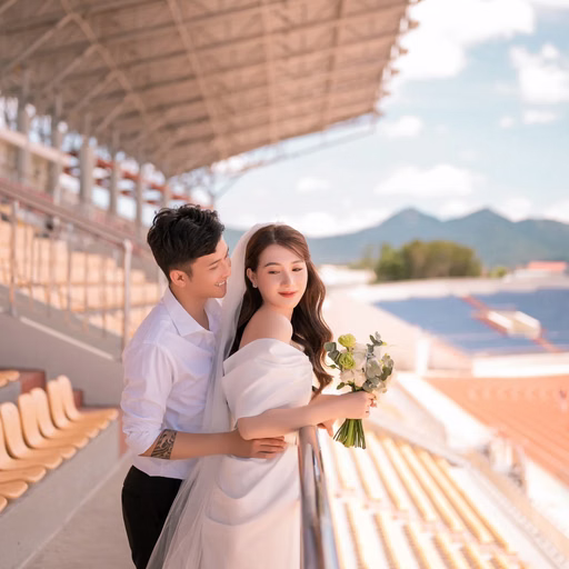 The couple embracing beneath the grandstand roof at Sân Vận Động Đà Lạt.