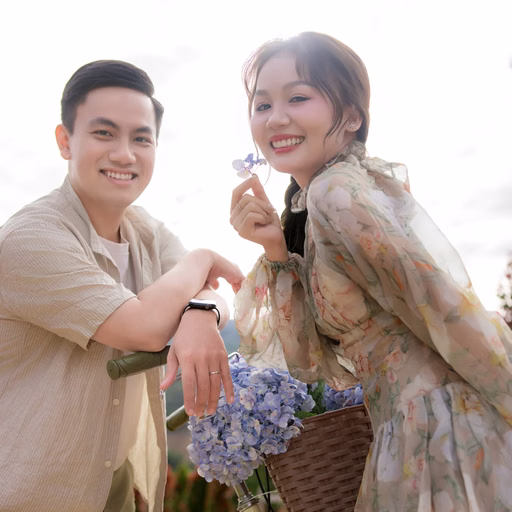 Cặp đôi cười bên xe đạp với bó hoa xanh tại Hoa Trong Rừng, Đà Lạt