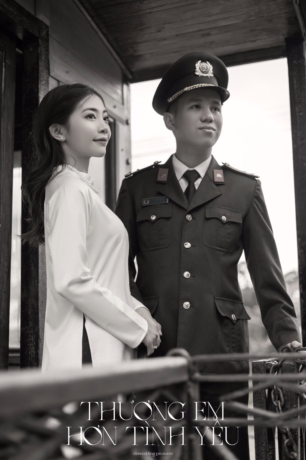 A black-and-white photograph of the couple beside a carriage door at Ga Đà Lạt.