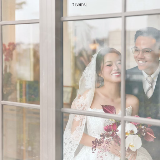 The bride and groom smiling through a glass doorway.