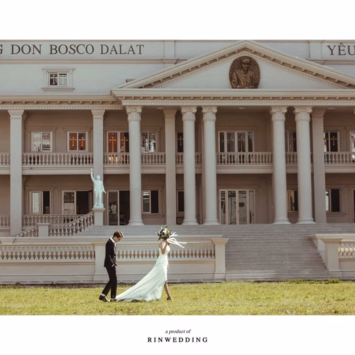 The bride and groom stand on the lawn before Nhà thờ Don Bosco