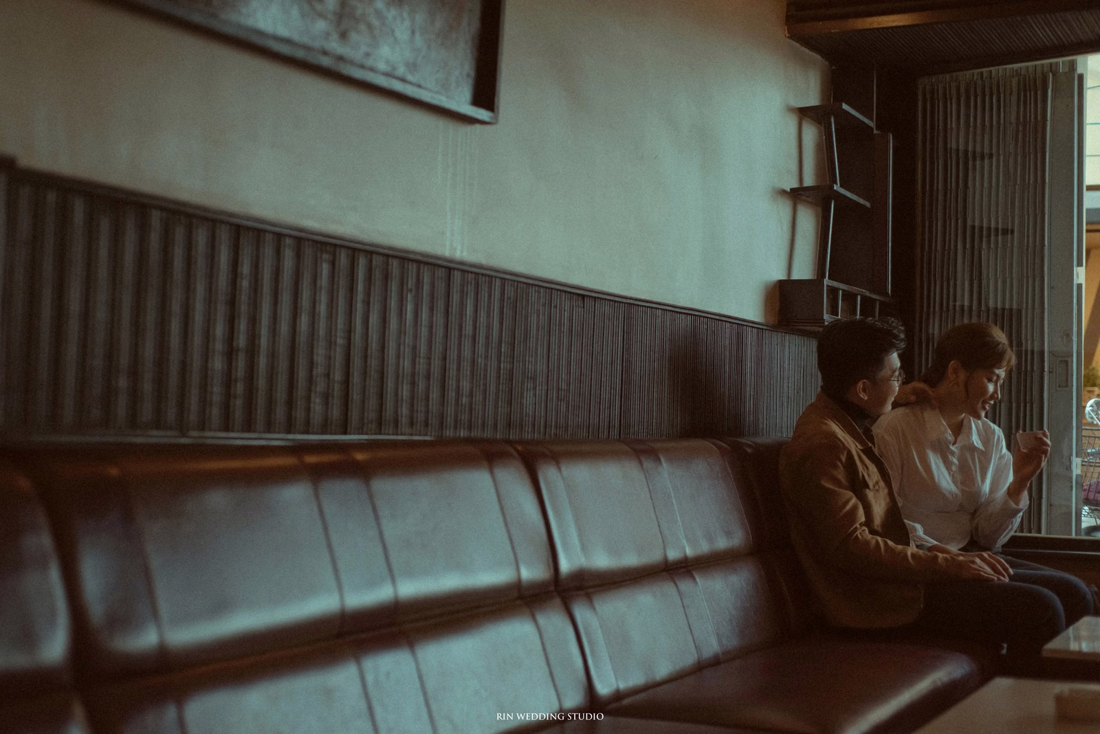 The couple sitting close on a long leather sofa in a nostalgic café.