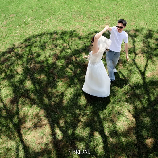 Overhead view of the couple turning with hands joined on the lawn in a pine tree’s shadow at Cây Thông Cô Đơn, Da Lat