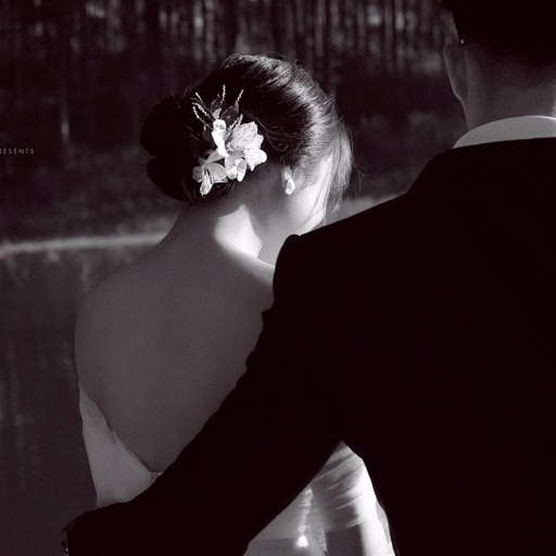 Black-and-white wedding photograph of the couple looking towards a lake.