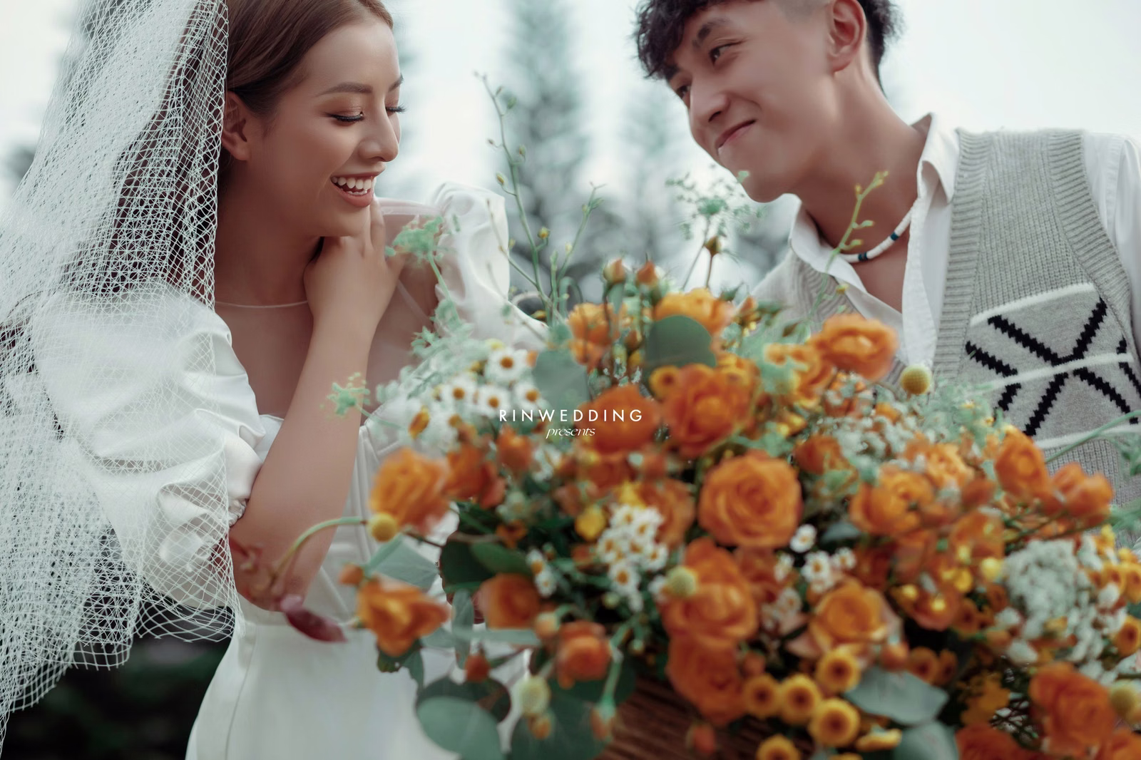 A close-up of the bride and groom with an orange and white bouquet.