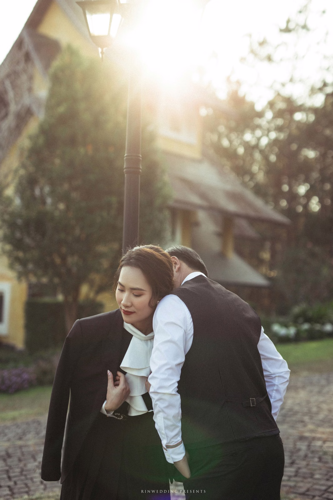 The groom carrying the bride on his back in a sunlit garden.