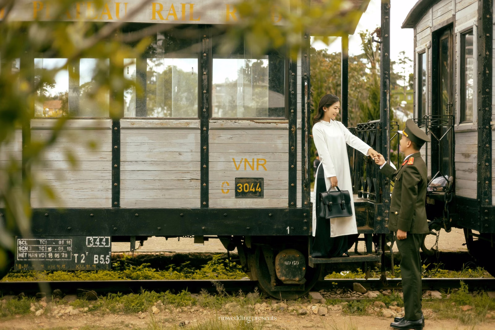 The couple stands beside a historic carriage doorway at Ga Đà Lạt.