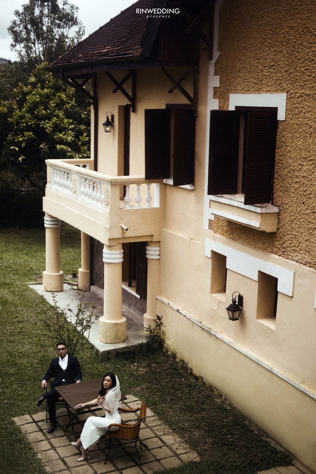An overhead view of the bride and groom before a yellow villa.